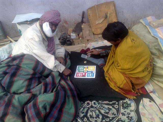 Prakash plays ludo with another patient at the pavement outside AIIMS canteen.